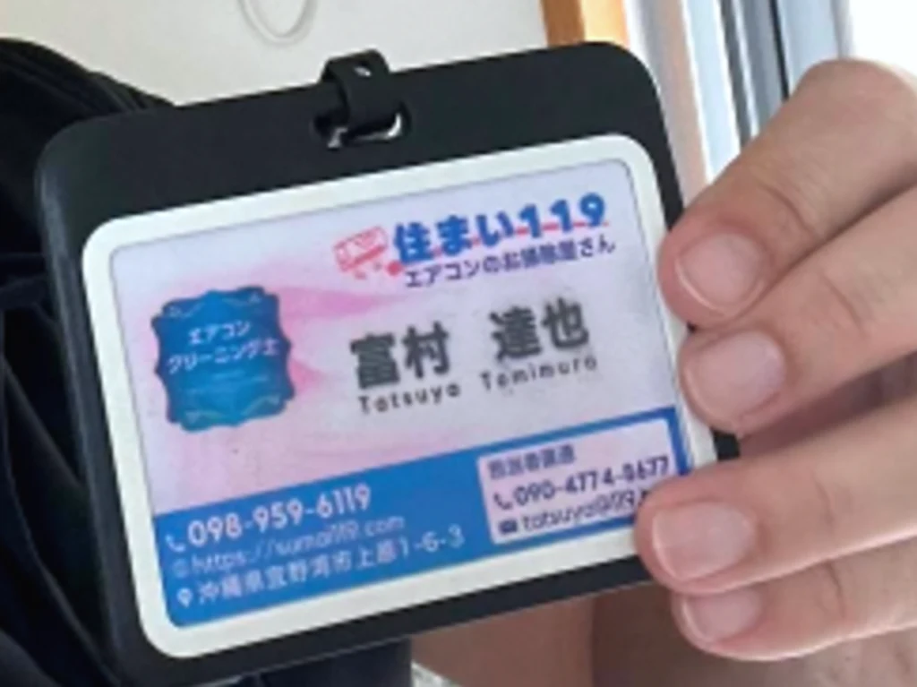 名札のクローズアップ。氏名・ローマ字・会社代表番号・携帯直通が印刷されている